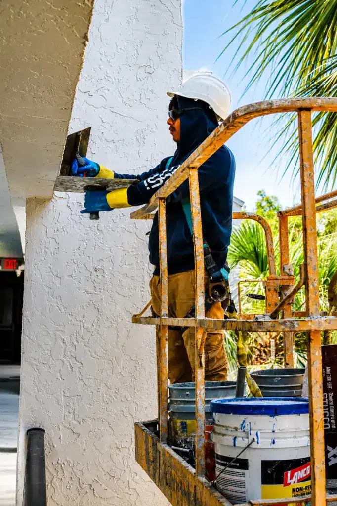 Worker-Applying-Stucco-To-Building-Exterior-On-Lift
