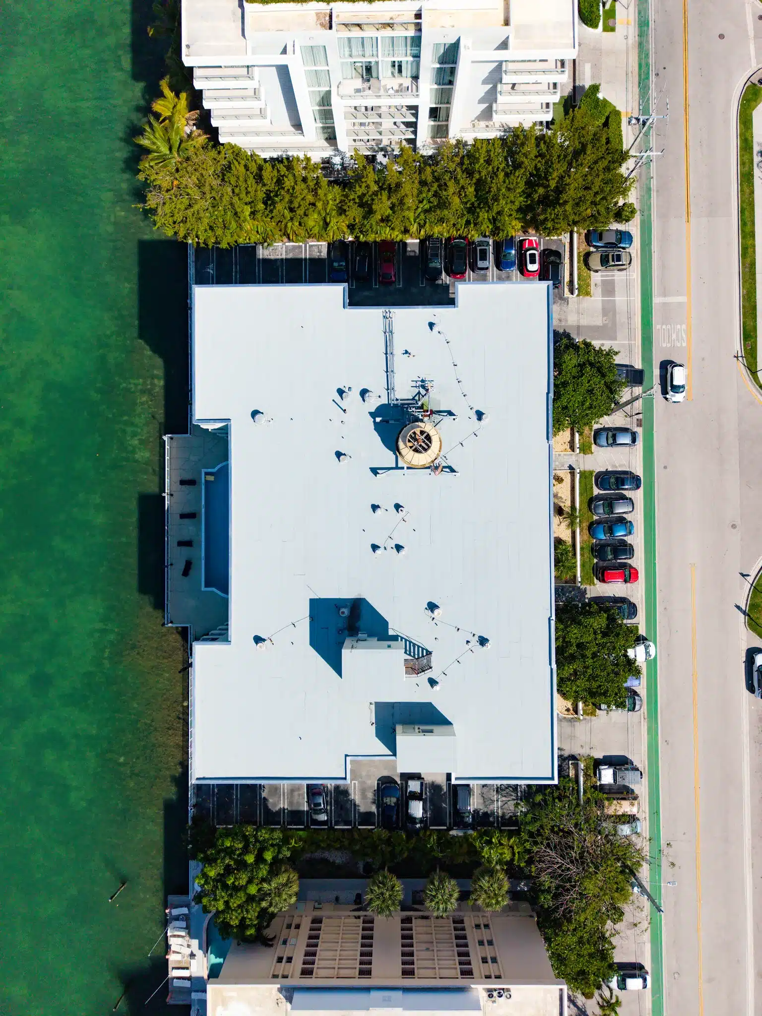 Aerial top-down view of a waterfront condo building with a new white roof coating in South Florida